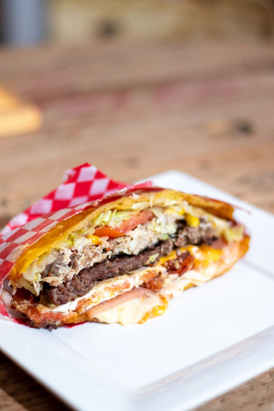Patacón Burguer relleno servido en plato con papel cuadriculado rojo