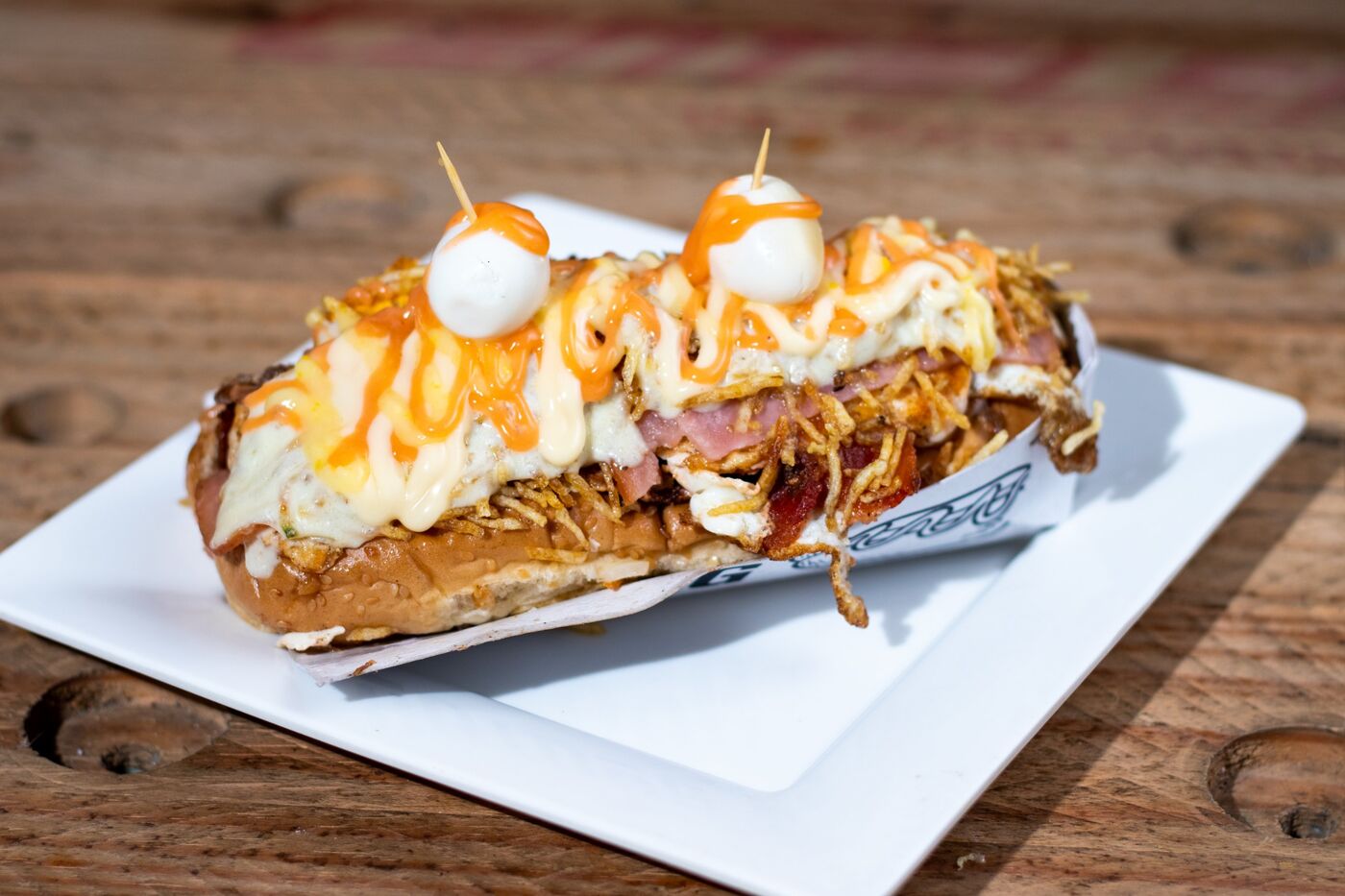 Perro caliente Super con ripio, queso gratinado, salsas y huevos de codorniz